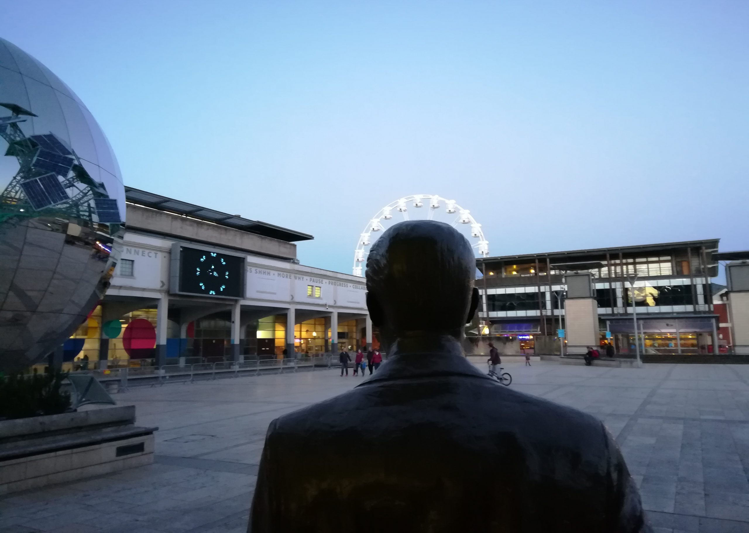 The Cary Grant statue in Millennium Square, Bristol, haloed by the ferris wheel