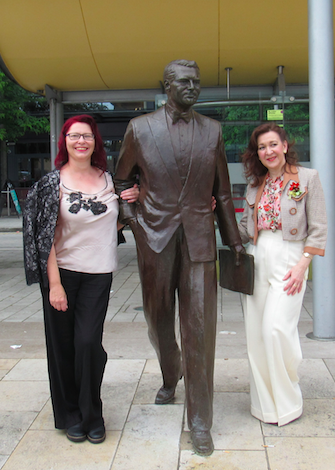 Festival-goers glammed up in vintage attire standing next to the Cary Grant statue in Millennium Square