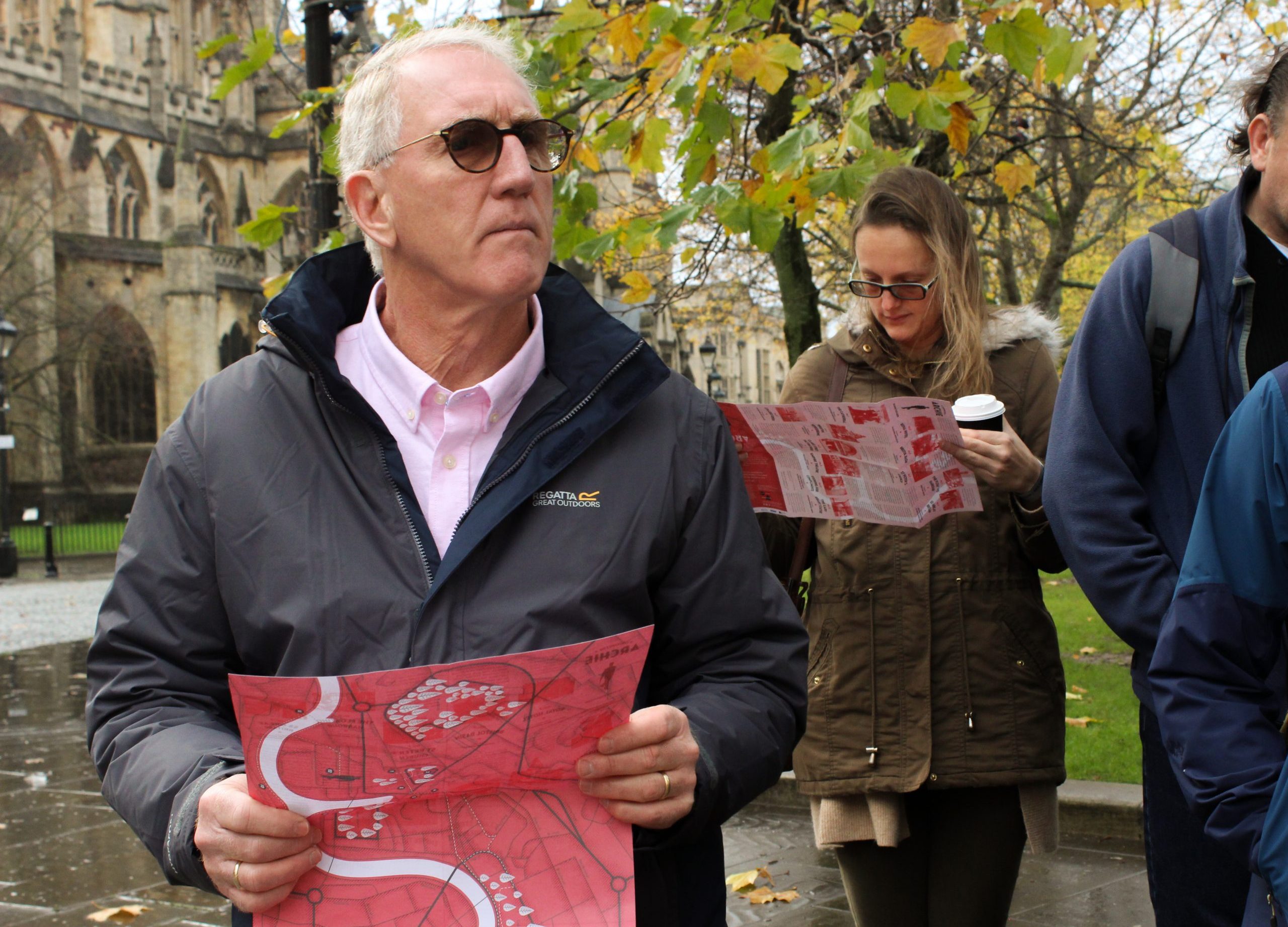 Participants in the Looking For Archie walking tour on College Green holding red maps