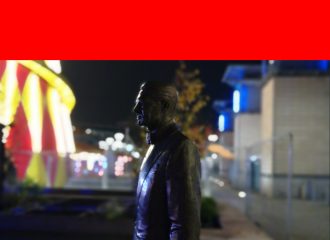 Cary Grant's bronze statue is in front of the brightly lit helterskelter at the Christmas Fair in Millennium Square